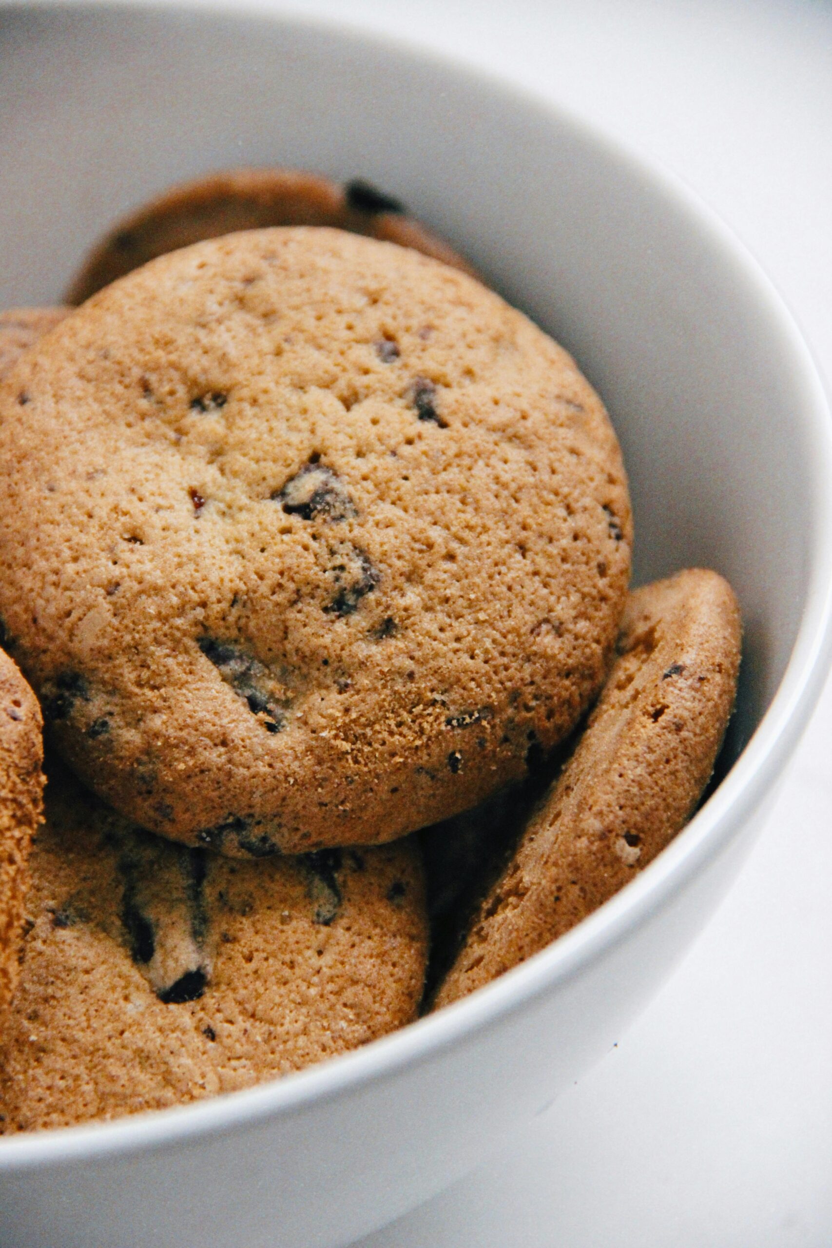 A close-up of freshly baked chocolate chip cookies in a white bowl, perfect for food blogs.